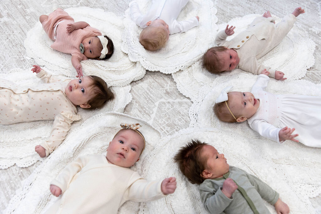 Group of babies laying in a circle on the floor