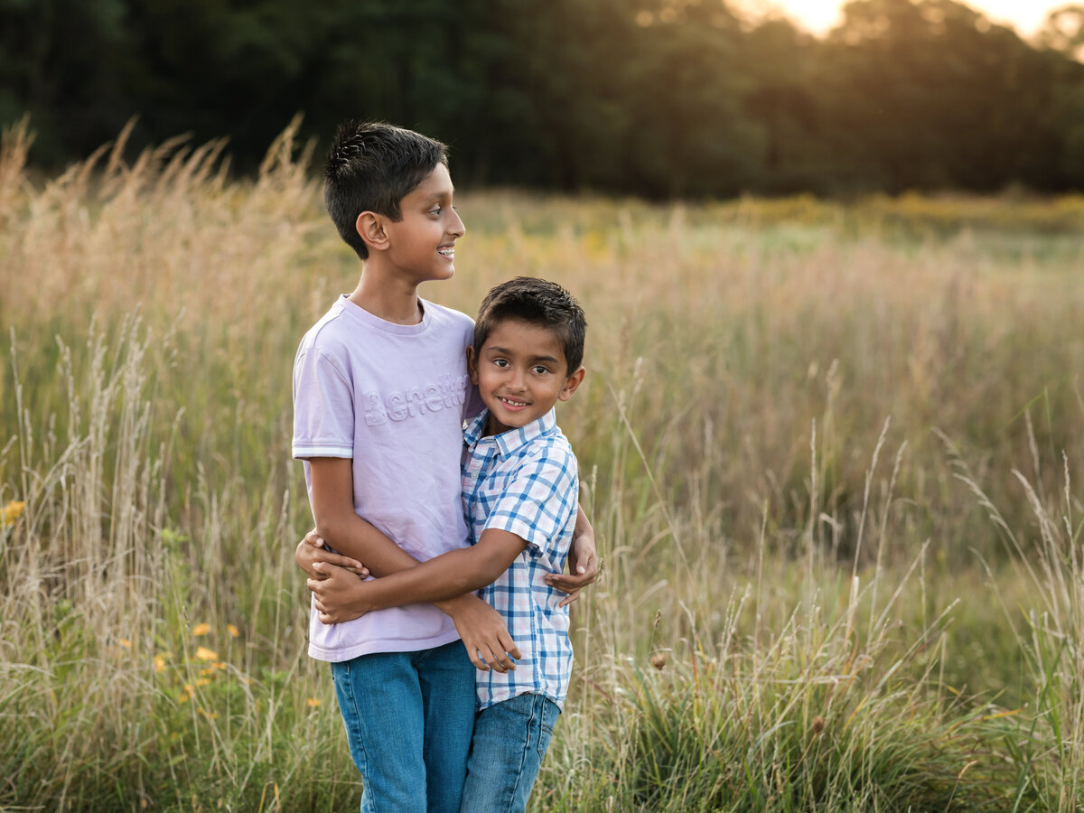 two brothers hugging in field for family photos