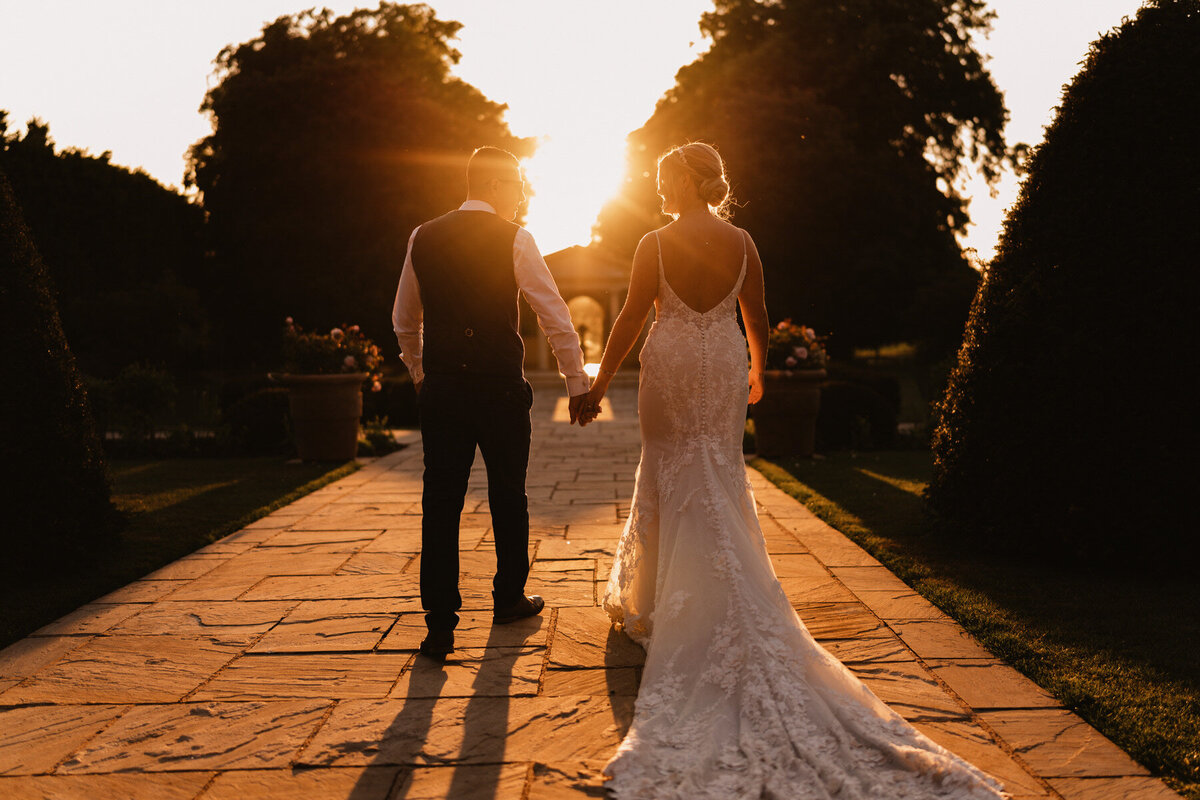 Bride and groom posing by the seaside railings at sunset at a luxury Lytham wedding venue, with soft pink skies and elegant wedding attire.