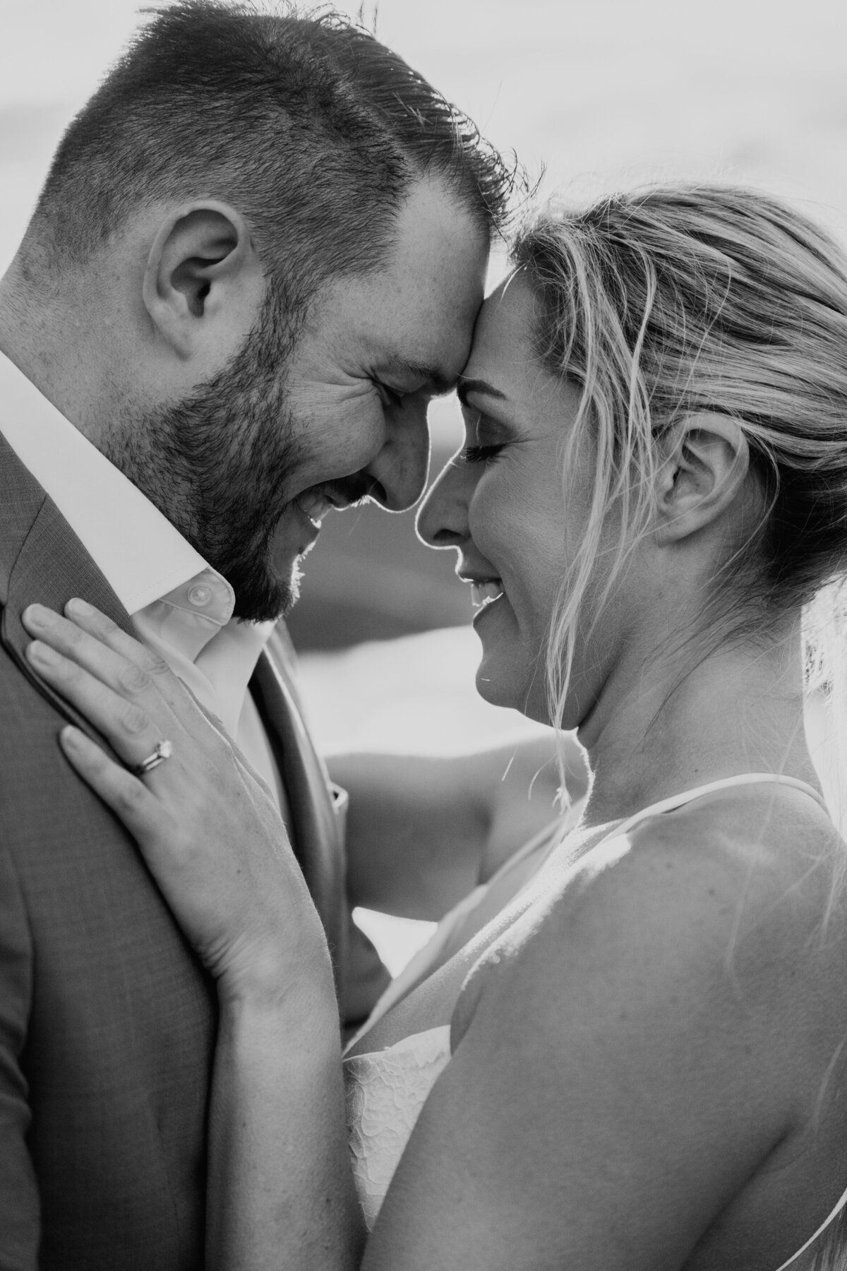 Forehead-to-forehead portrait of couple smiling in soft light