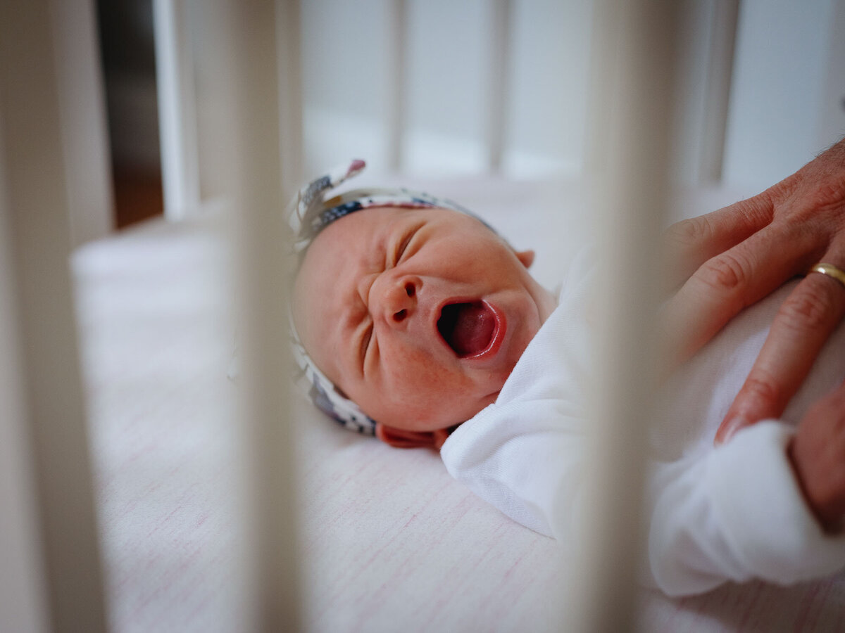 Newborn baby girl yawn in her crib.