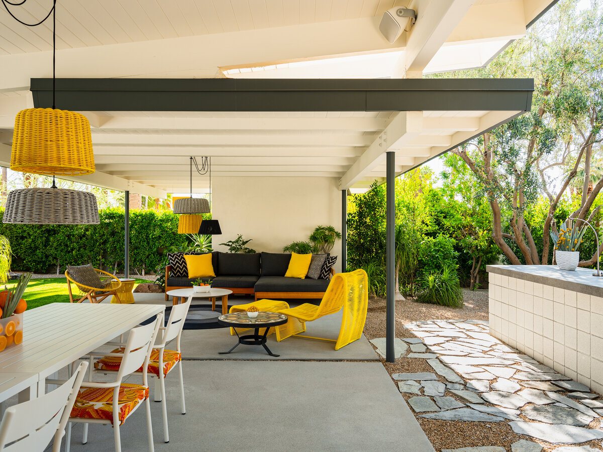 Outdoor kitchen at cabana in midcentury modern home with yellow accent outdoor furniture.