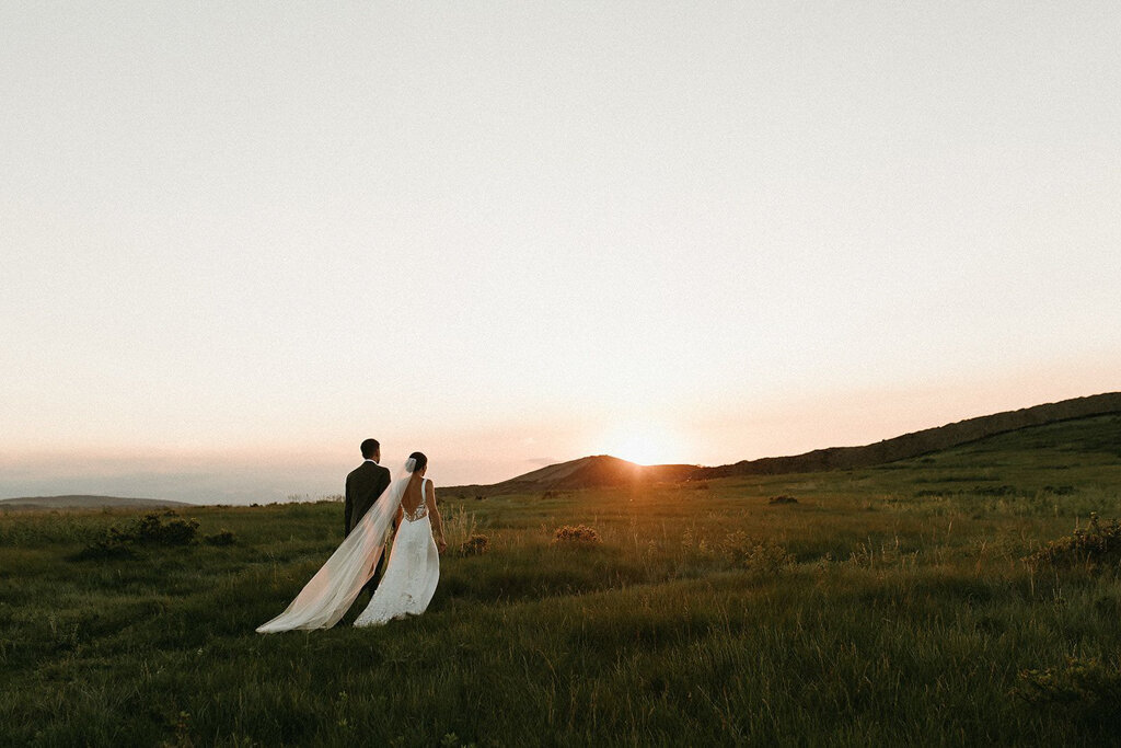 Bride and groom walking together during sunset by Court Amber Photography, joyful and adventurous wedding photographer in Calgary, Alberta. Featured on the Bronte Bride Vendor Guide.