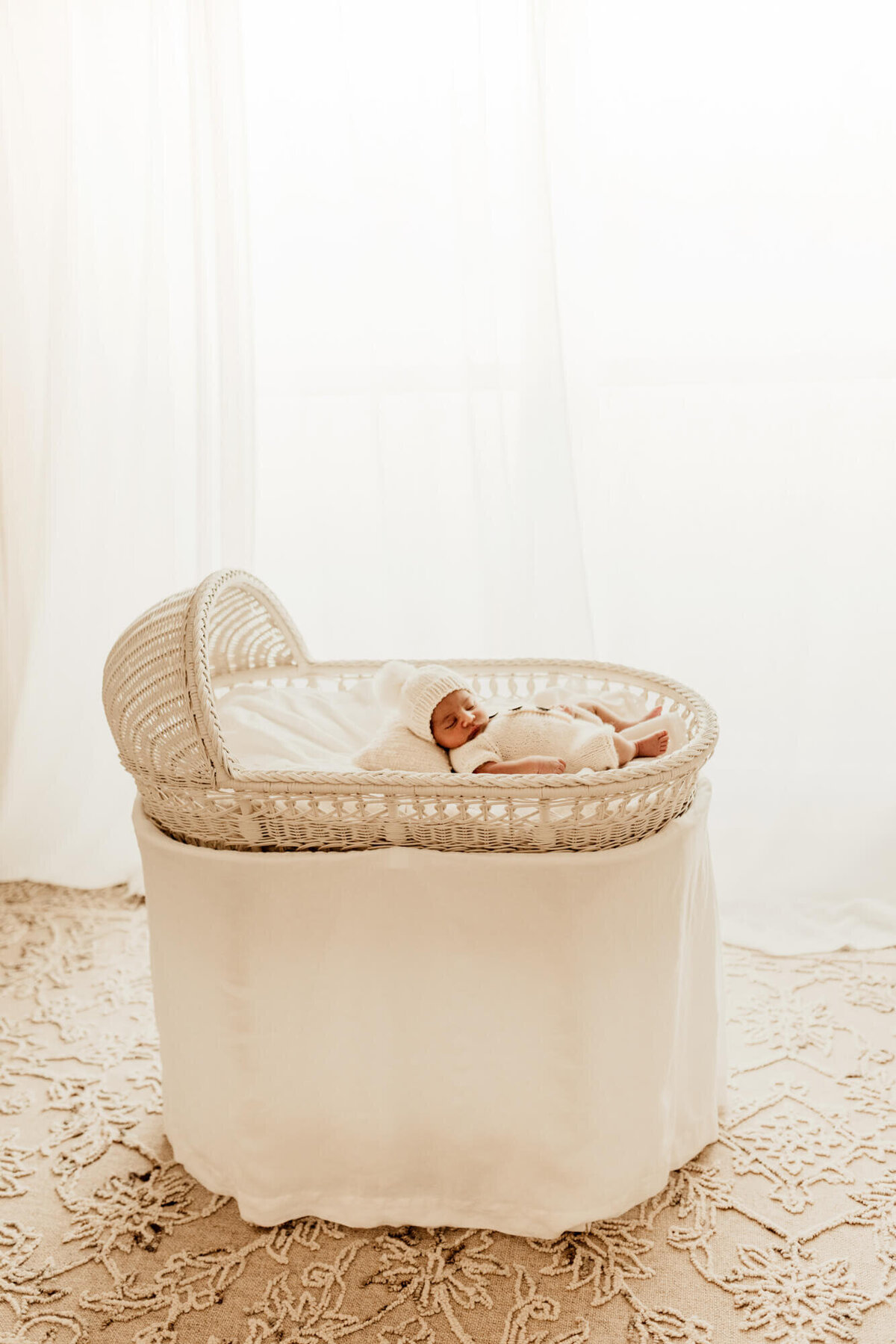 Newborn baby boy in a white wicker bassinet.