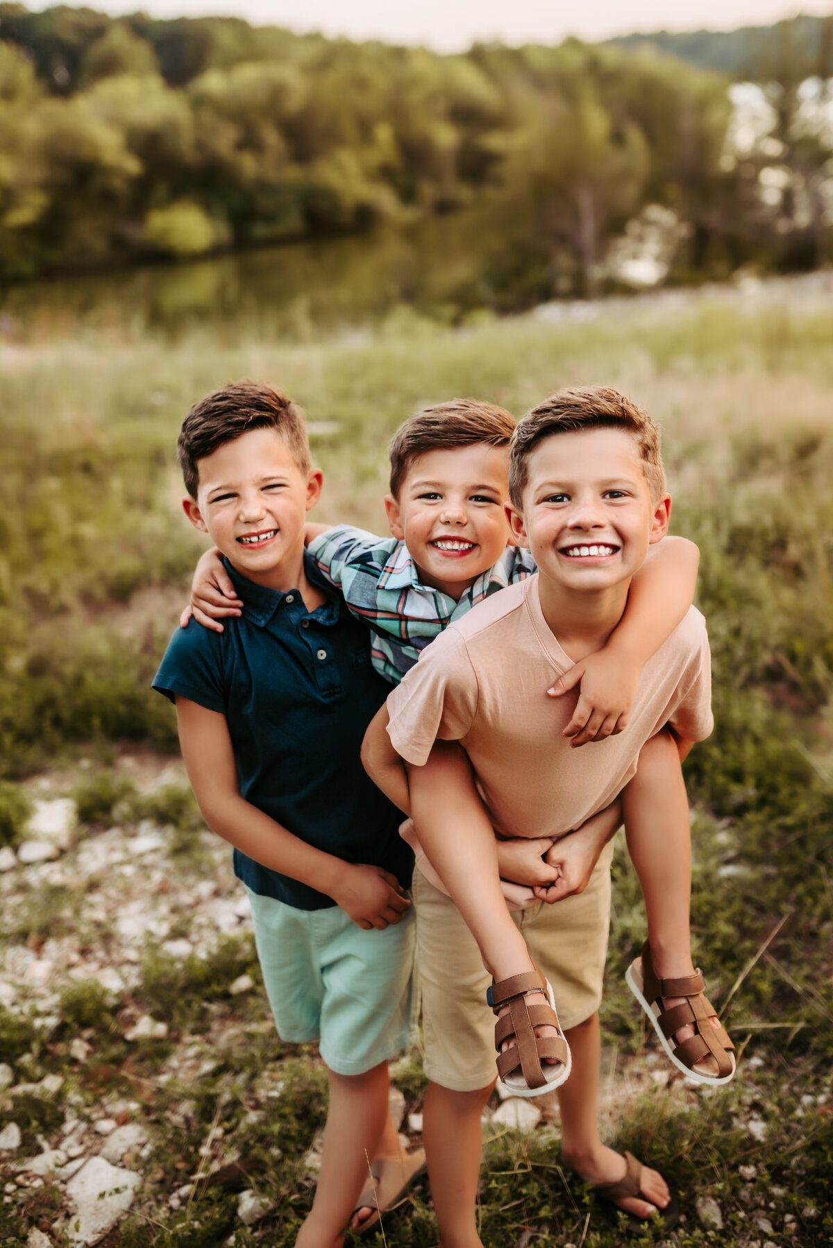 Three brothers give piggy back rides and smile at the camera