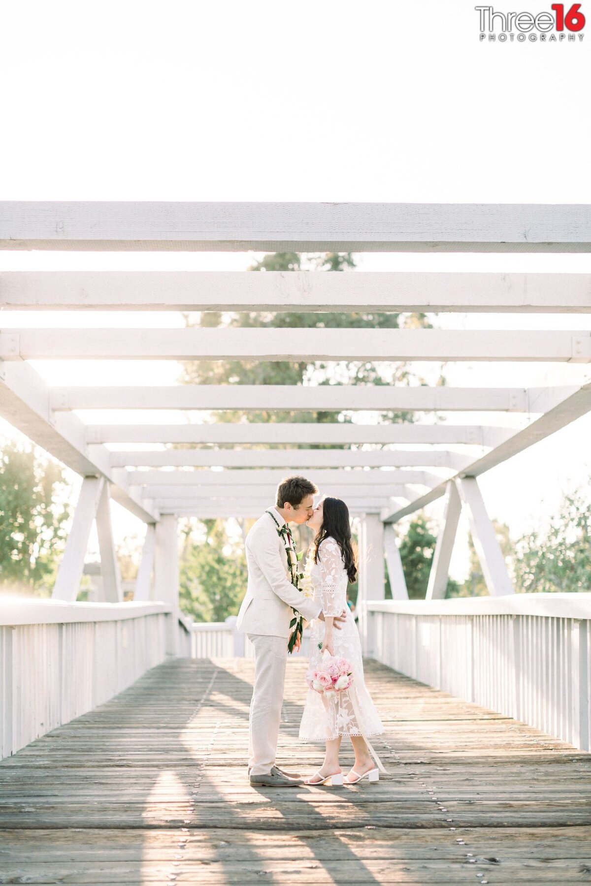 Bride and Groom share a tender kiss on the bridge that goes over the Mike Ward Community Park