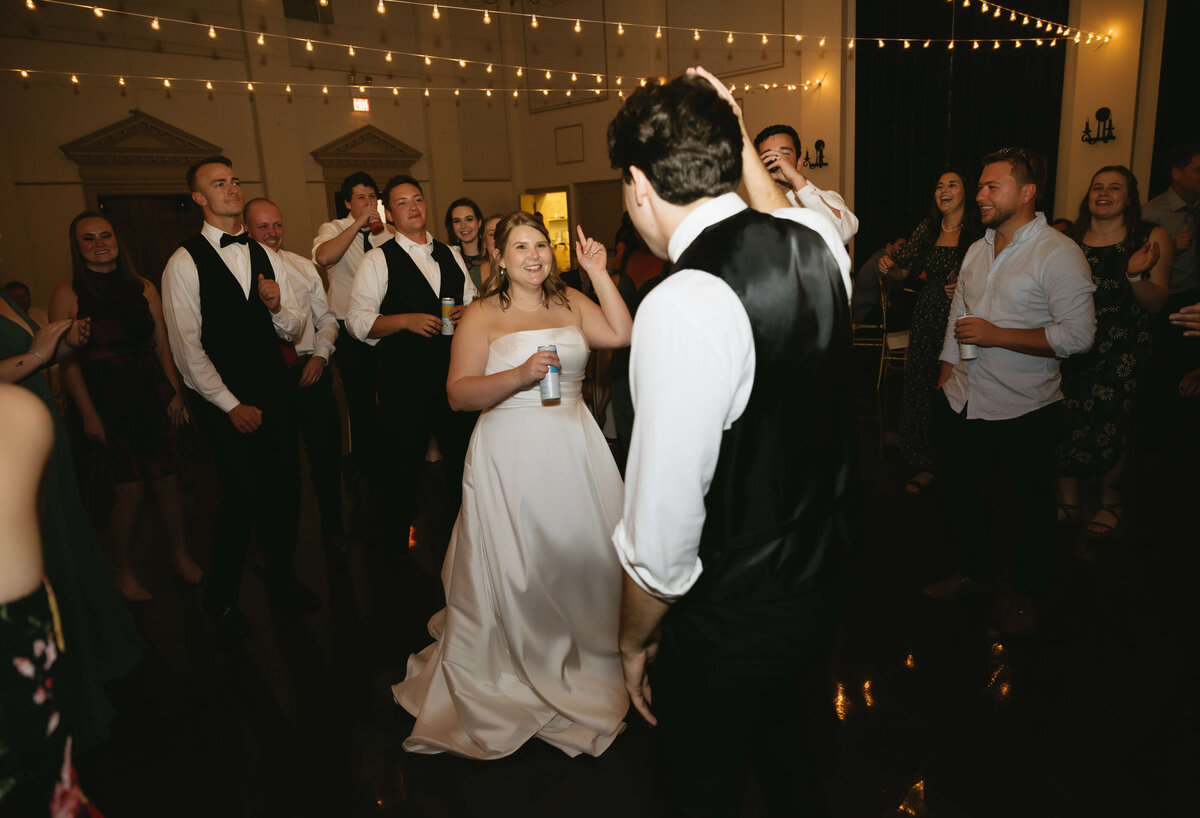 wedding reception inside a grand hall at middleburg community center with twinkle lights strung over head as the bride adn groom dances with thier family and friends during their Richmond wedding