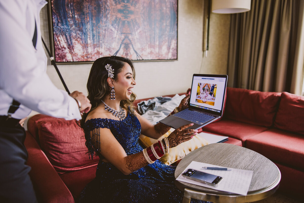 An indian bride happily looking at her wedding photos on the laptop