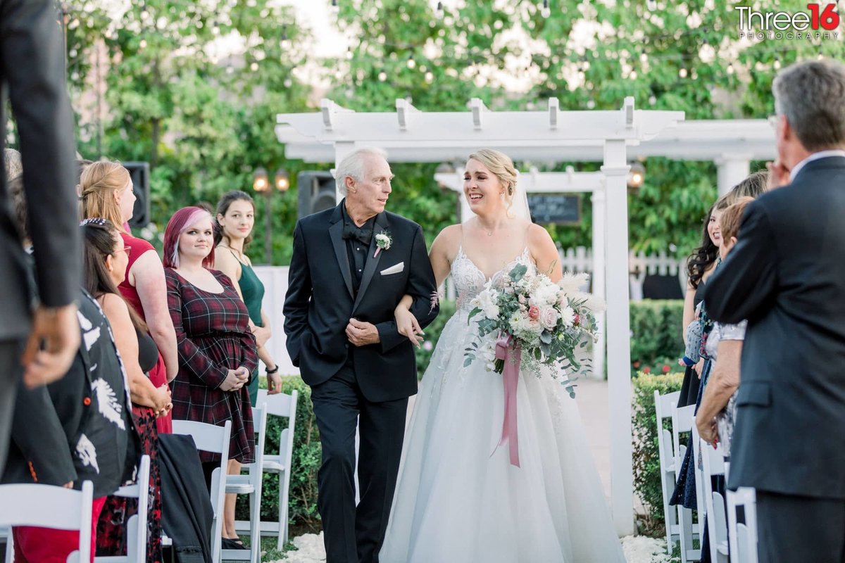 Father of the Bride escorts his daughter down the aisle towards the altar