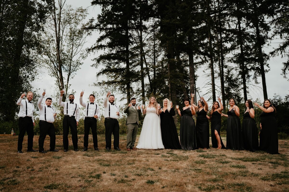 Full wedding party in black right before they take a shot together