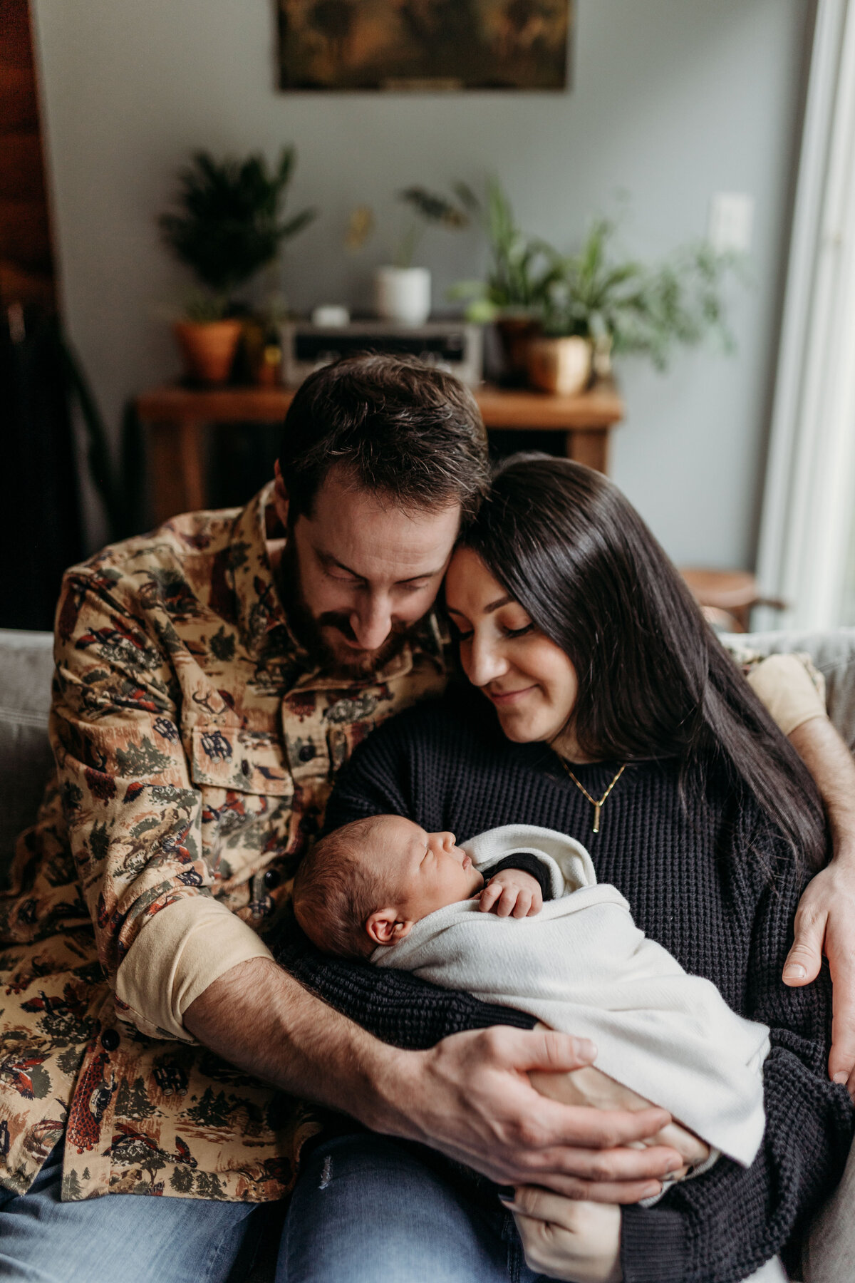 A couple sits inside their Vancouver Washington home admiring their newborn baby