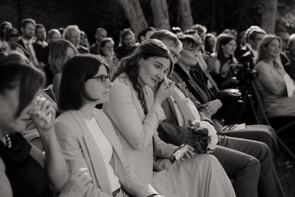 Une invitée essuie une larme d'émotion pendant la cérémonie de mariage au château de beaussais. Par Kamescop, photographie et film de mariage en Bretagne.