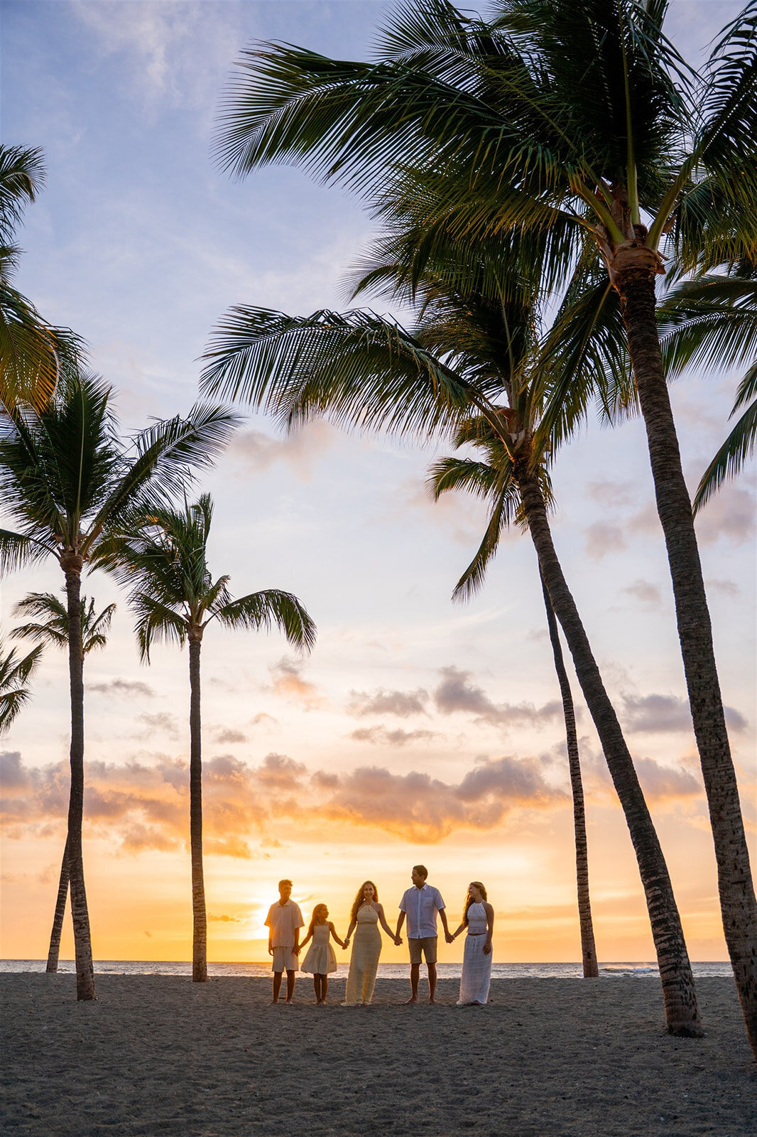 Sunset photo with family holding hands in Kona, taken by big island family photographer