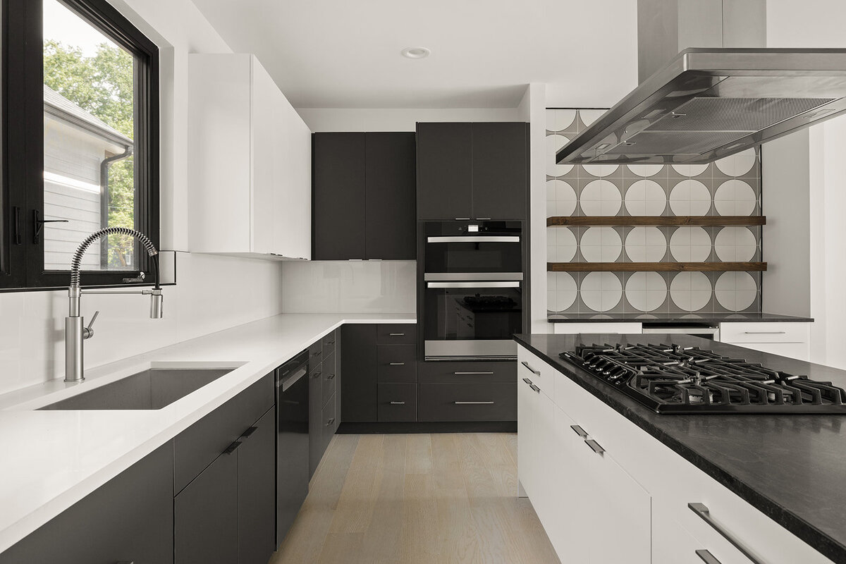 two-toned modern kitchen with black countertops and decorative tile backsplash