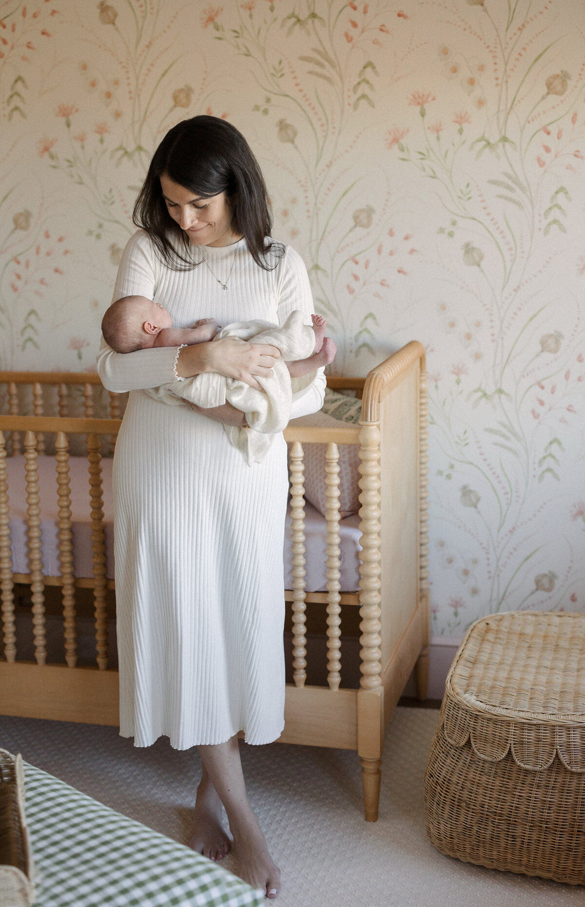 Women holds newborn in nursery during Boston newborn session.