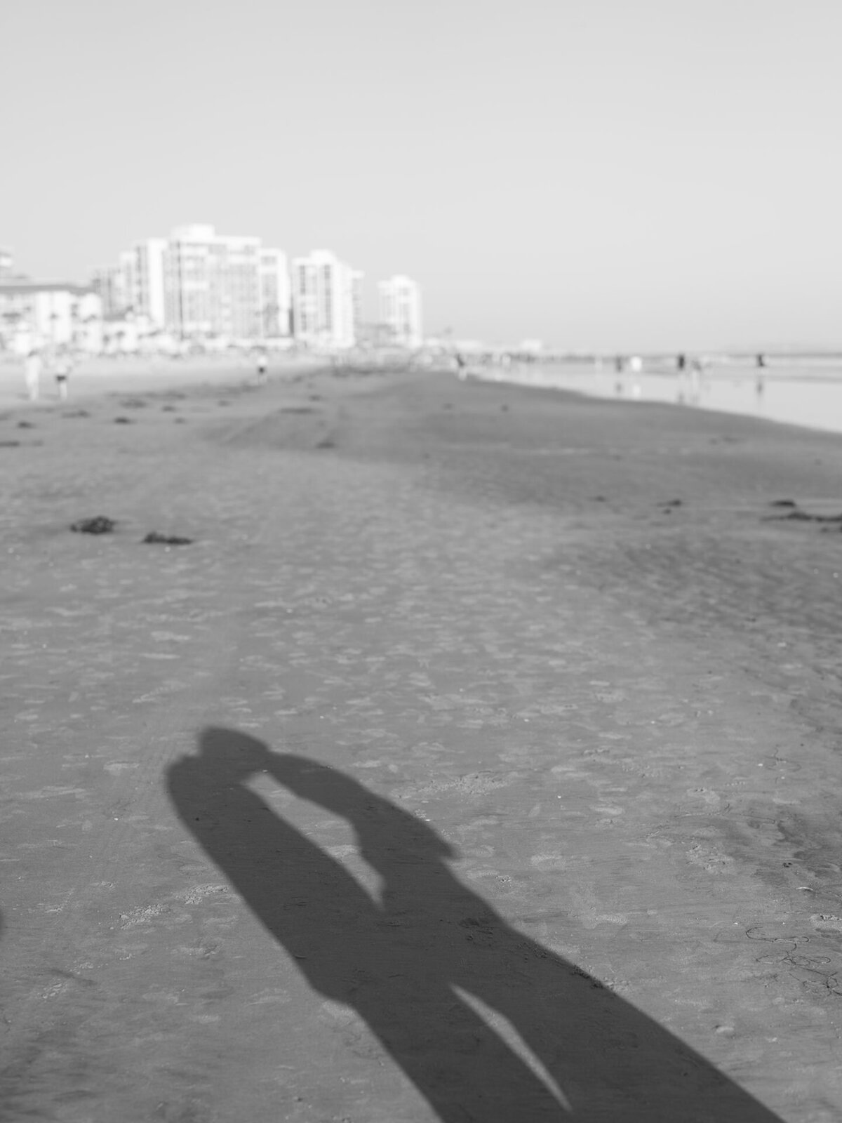 shadow of husband and pregnant wife at san diego beach