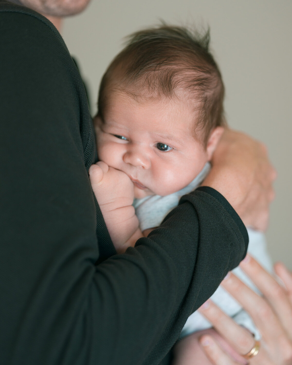 Newborn baby sleeping in a parent's arms, photographed by a top Los Altos newborn photographer. Expert baby photography in a cozy setting.