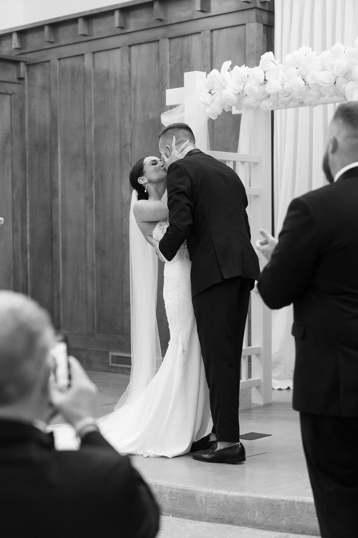 Bride and groom sharing first kiss at altar during wedding ceremony