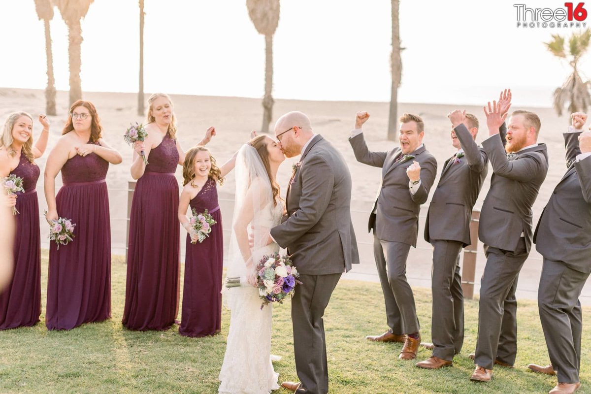 Wedding party cheers on the couple as they share a kiss