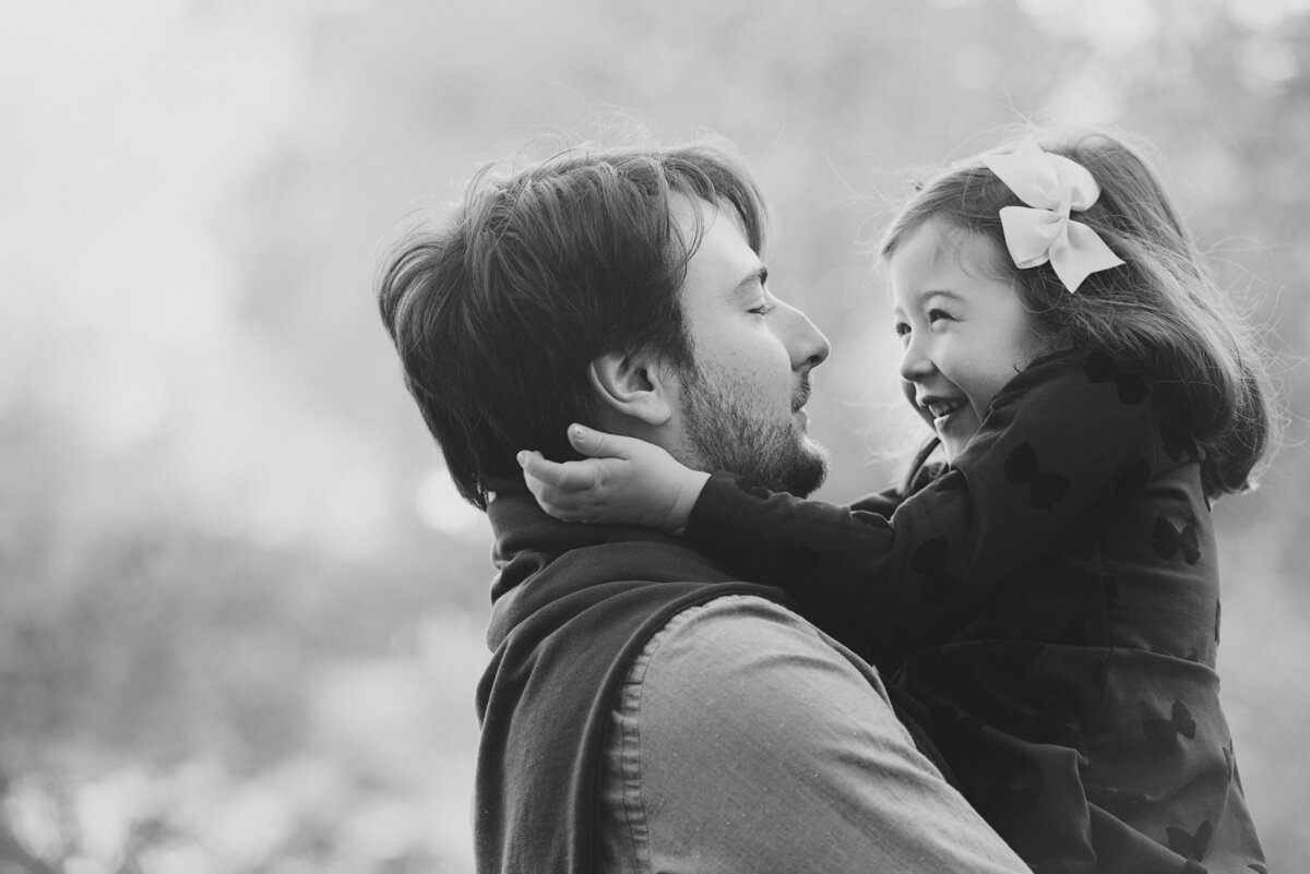A child smiling as they are being held by their parent