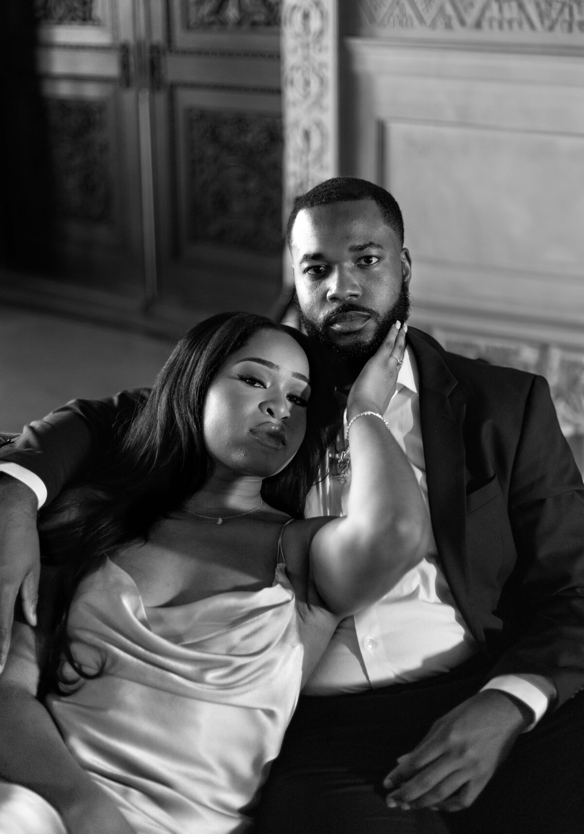 Ochre Court Mansion  | Kelsey Sheehan Photography Timeless Rhode Island Weddings | A couple sits closely in an elegant setting, both displaying a serene and intimate expression. The woman rests her head gently on the man’s shoulder.