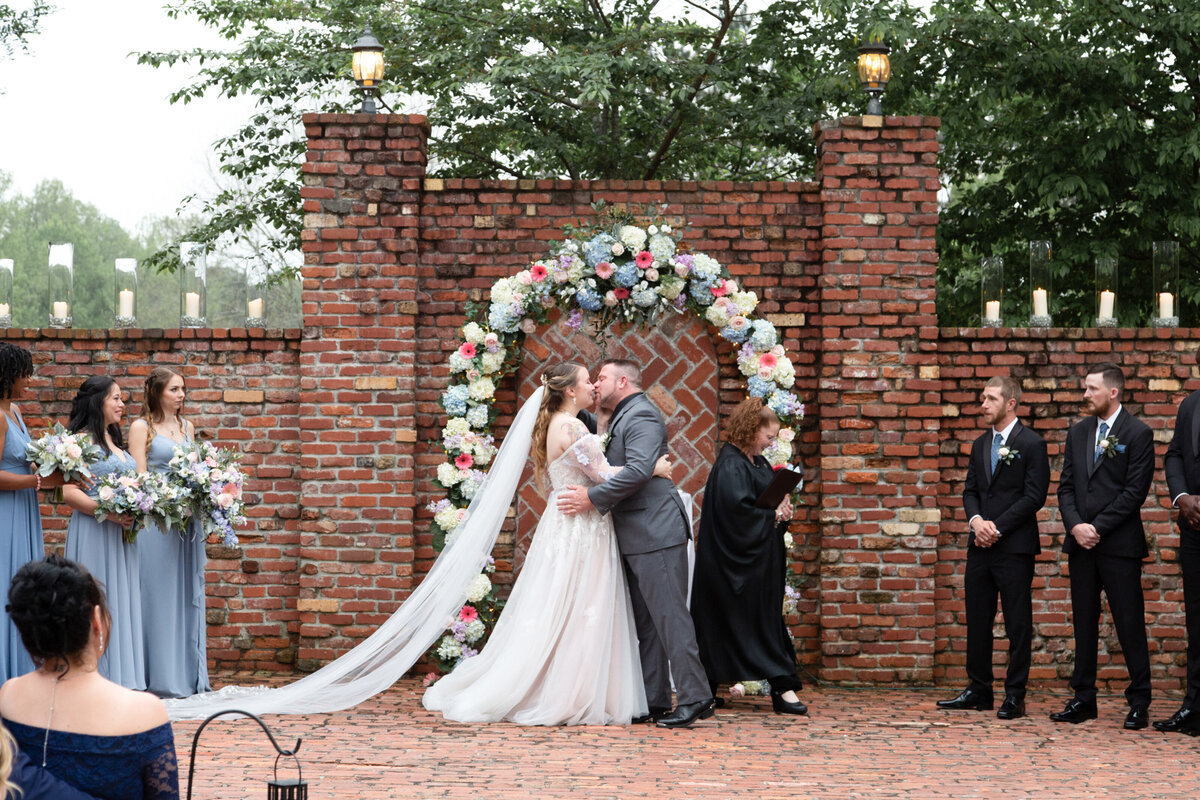 Carl-House-Wedding-Bride-and-Groom-First-Kiss-Floral-Arch