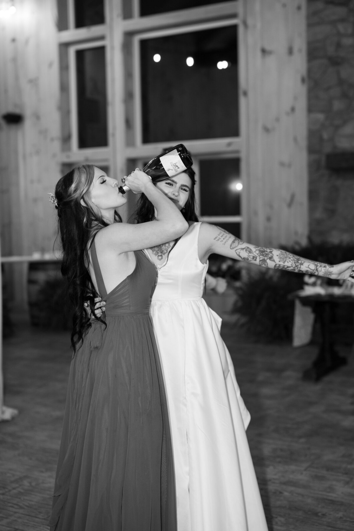 A bride dancing with a guests drinking from a champagne bottle.