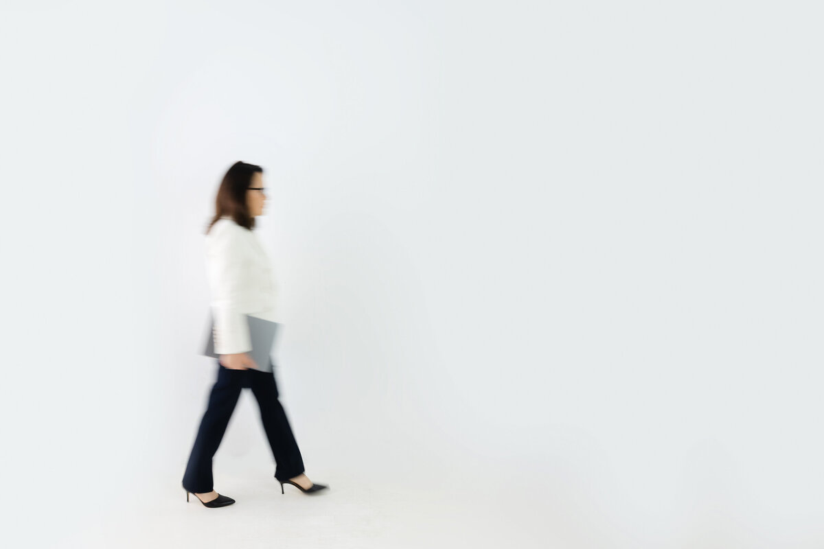 Professional woman walking with laptop symbolizing movement and leadership in action