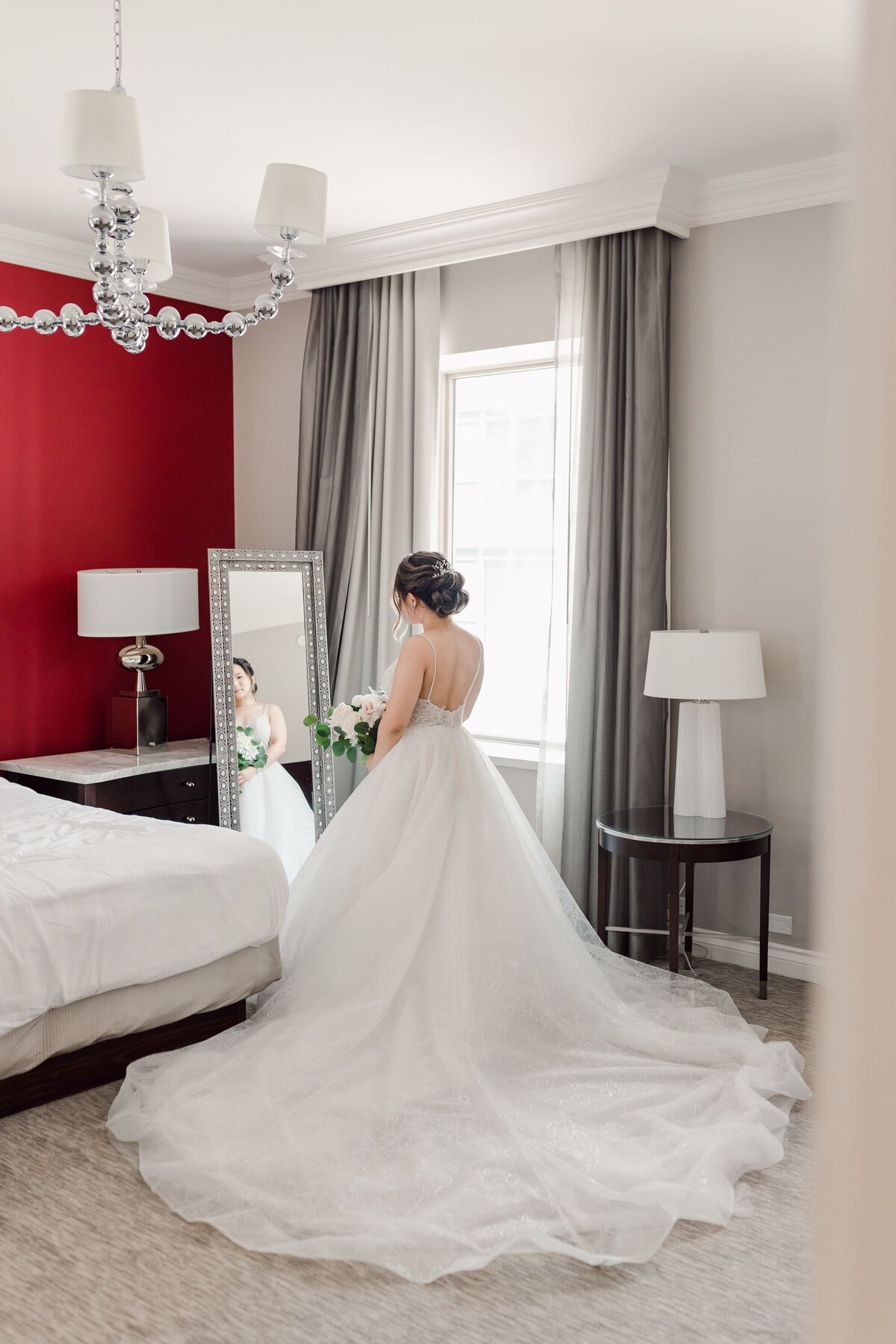 Bride in wedding dress looking in hotel room mirror
