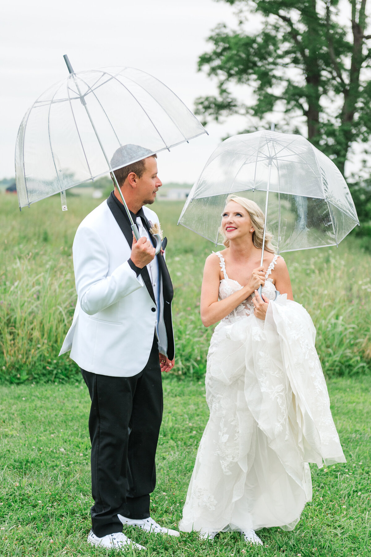 Bride and groom with clear umbrellas due to rain at The Farmstead in Harrodsburg