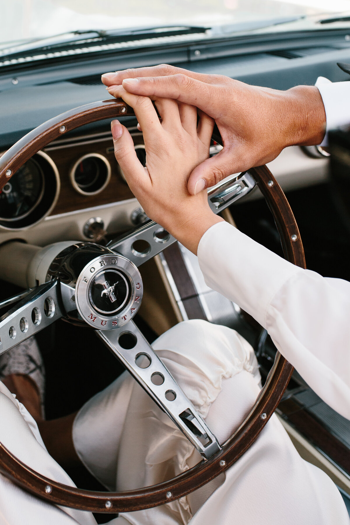 The Lovers Elopement Co - eloping couple join hands on steering wheel in open top car through Queenstown New Zealand