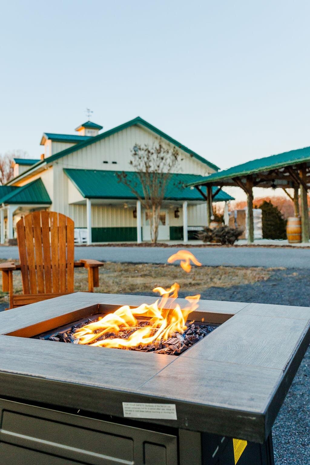 The green-roofed exterior of Willow and Stone Events, featuring a cozy firepit with Adirondack chairs, perfect for weddings and celebrations near Charlotte, NC