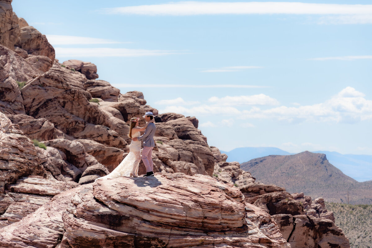A newlywed couple standing on a rocky overlook