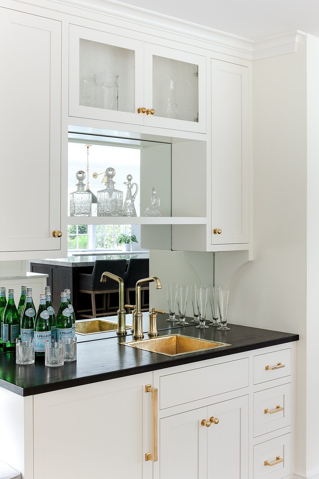white wet bar with black countertop and gold sink