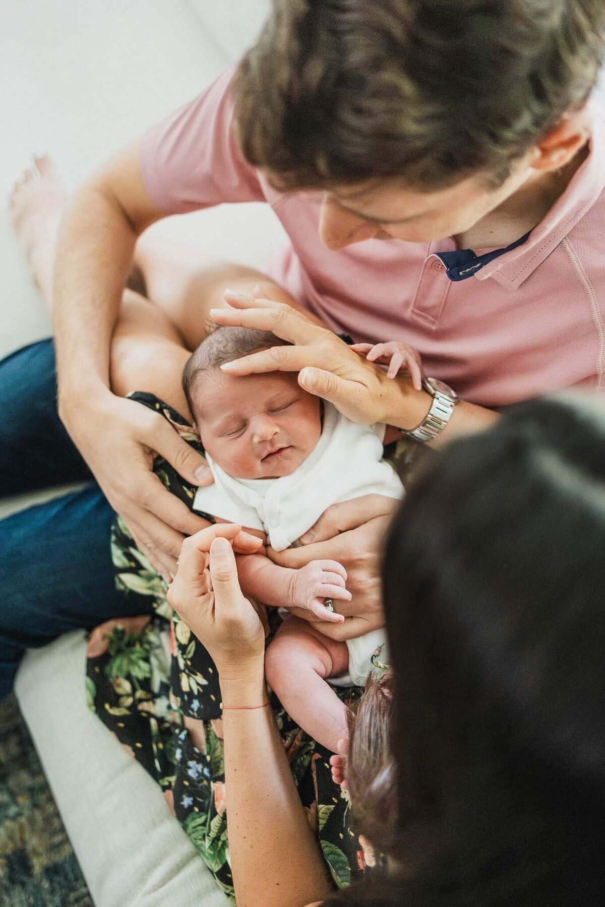 Parents gently cradle their newborn in a serene moment. Captured by a Cleveland newborn photographer specializing in lifestyle newborn photography.