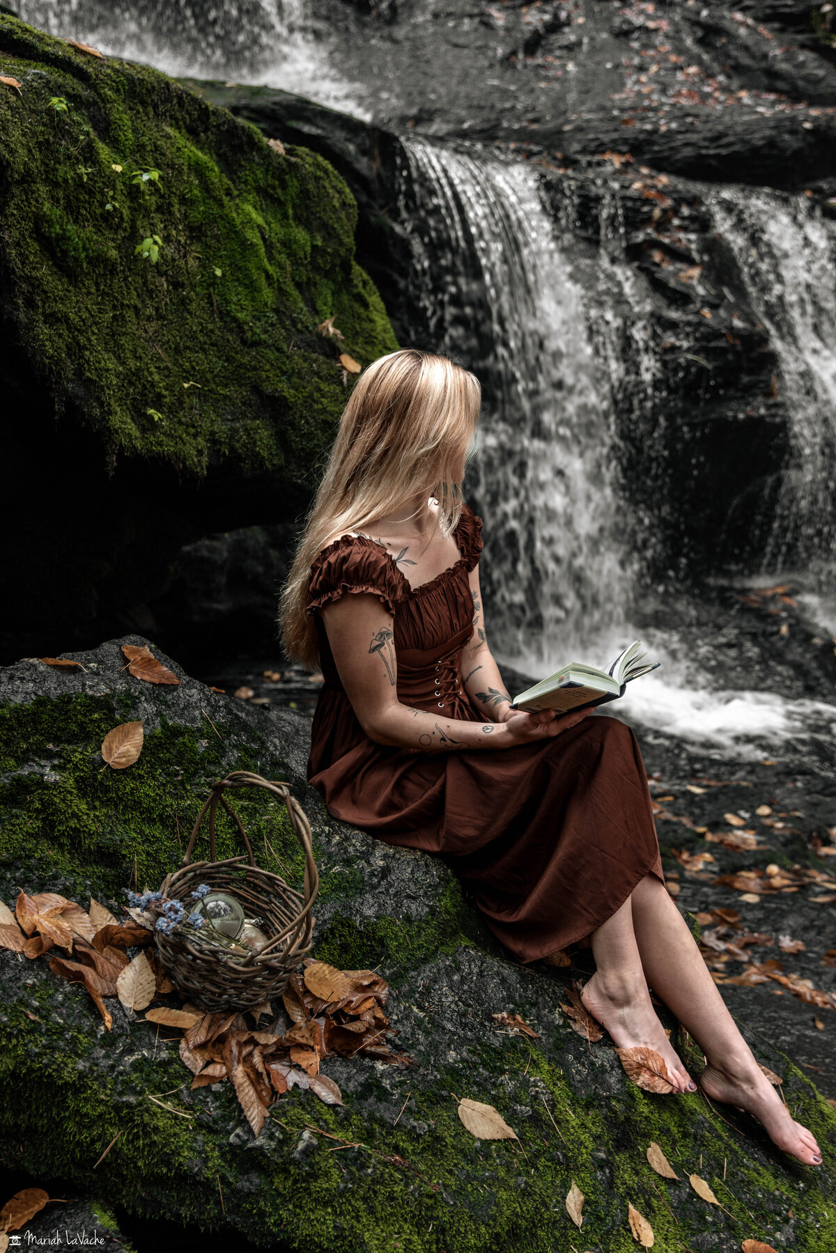 woman sitting on waterfall holding book