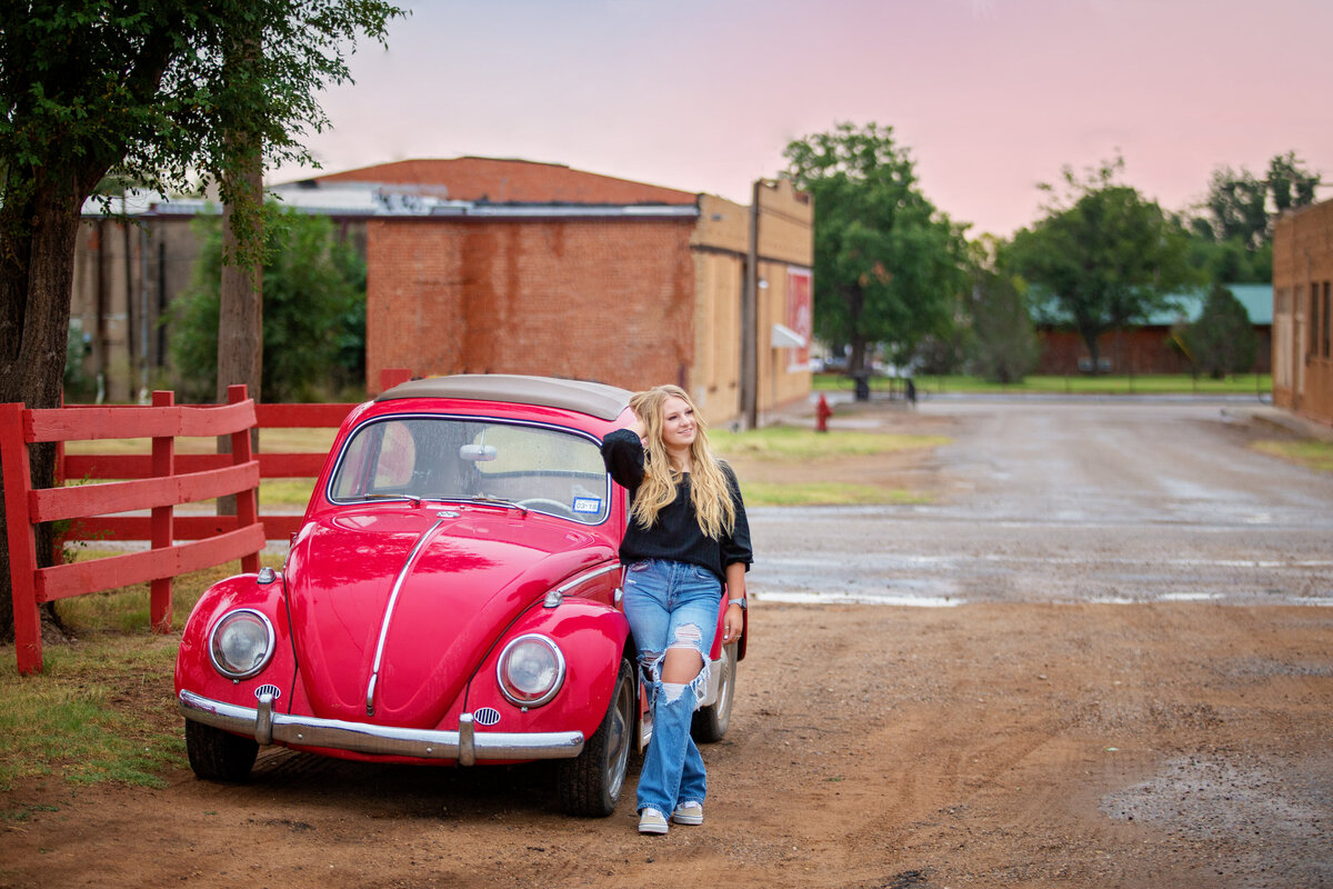 Senior girl standing next to red VW bug car Turkey Tx