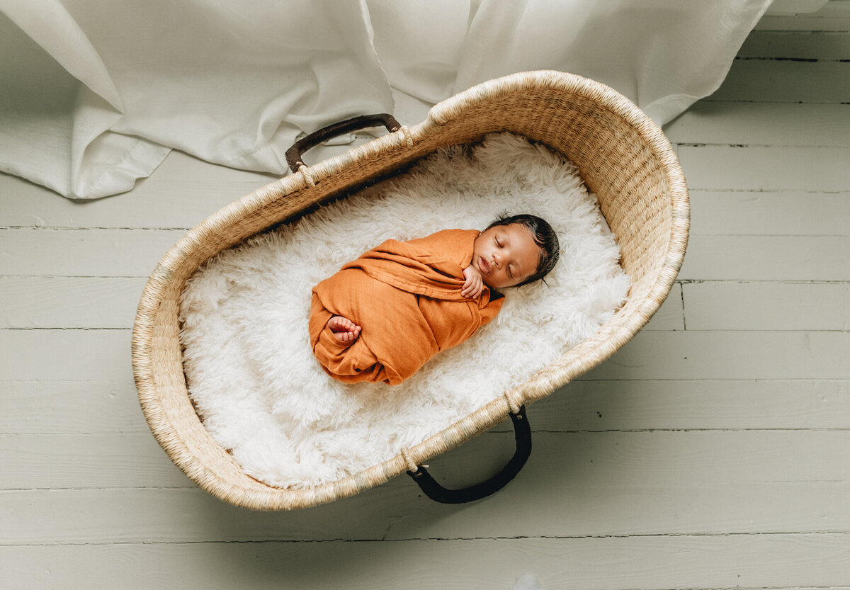 Newborn photographer capturing a newborn baby sleeping in a crib