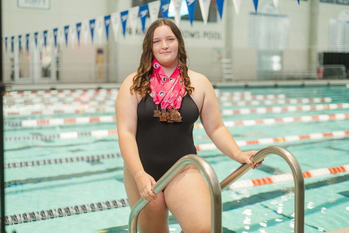 a high school grad wearing a swim suit and her swim medals