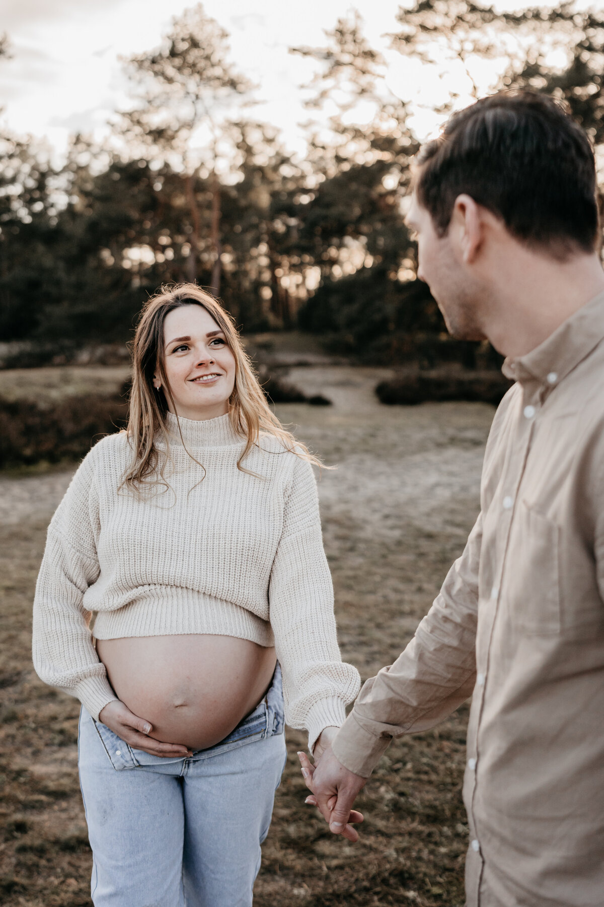 Zwangere vrouw loopt hand in hand met man in de Soesterduinen.