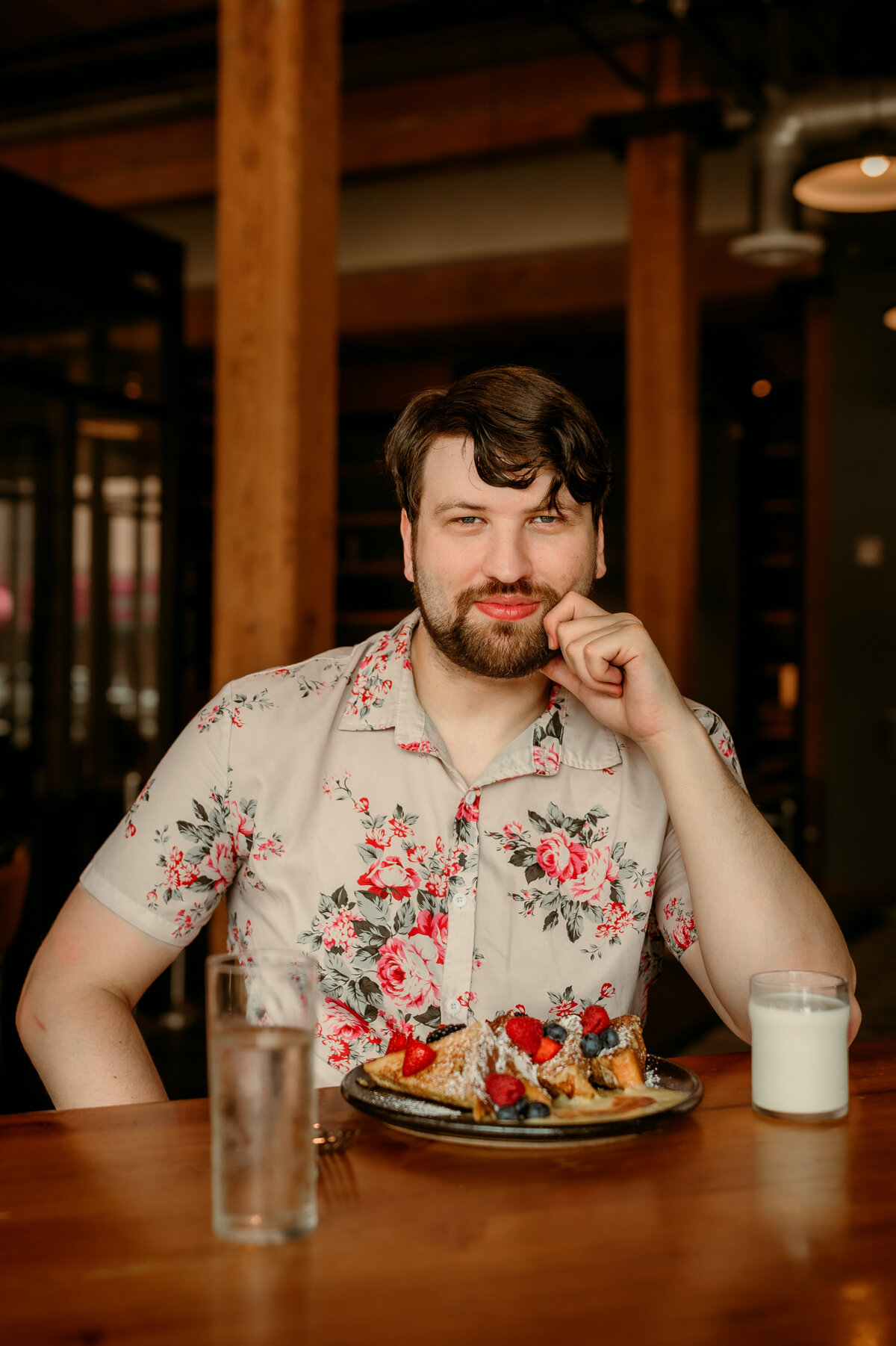 Polished online dating profile photo of man in a floral shirt at a restaurant, confident and well lit.
