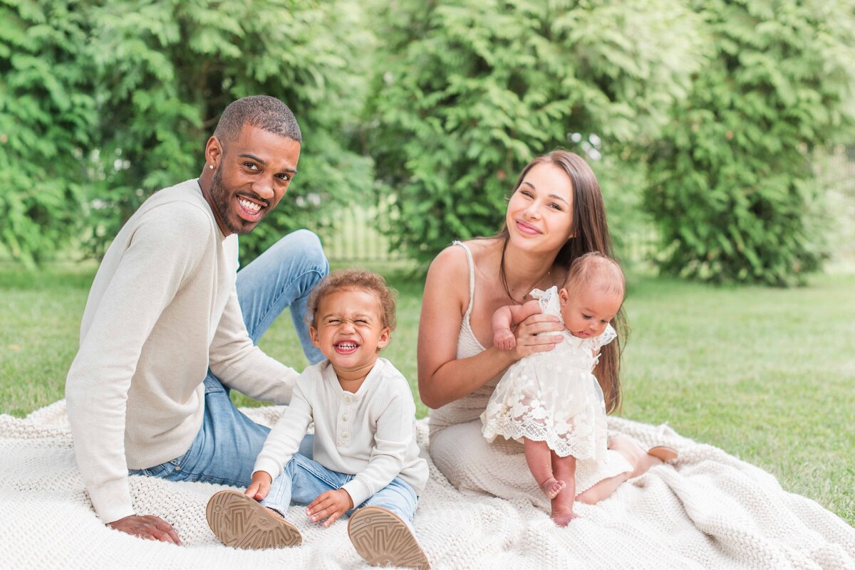 mixed race family on picnic blanket smiling neutral outfits