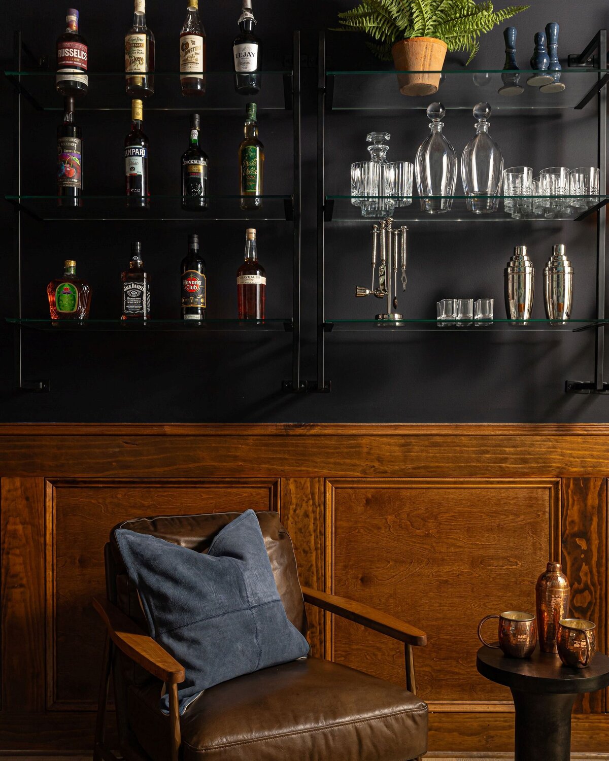 lounge with dark walls, wood paneling, and leather chairs