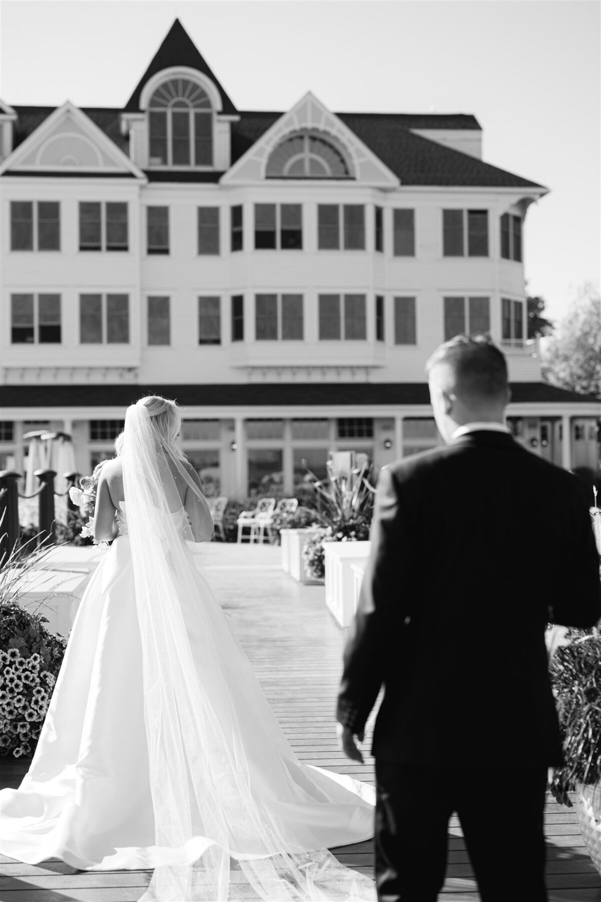 Groom watching his bride as she walks away from him on the dock of Hotel Iroquois on Mackinac Island