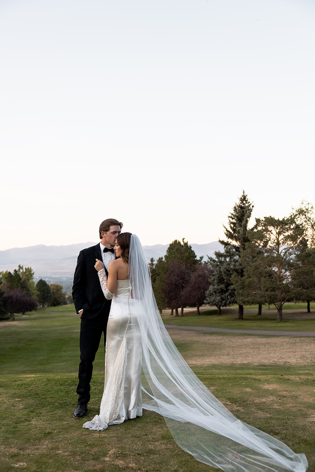 Best Montana wedding photographer portfolio: couple walking hand-in-hand through a grassy field, capturing an elegant, editorial moment.