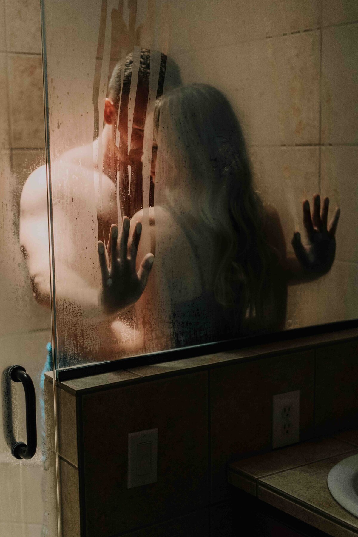 A couple steams up the shower and leaves hand marks on the glass