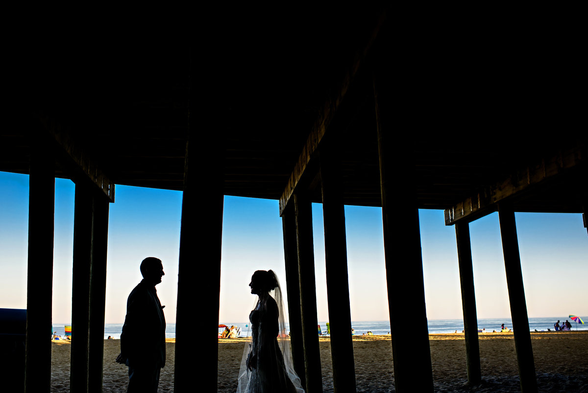A bride and groom under the pier in long branch, NJ.