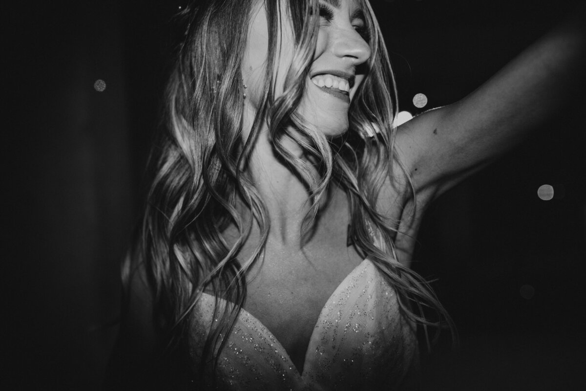 Black and white photo capturing a joyful bride dancing
