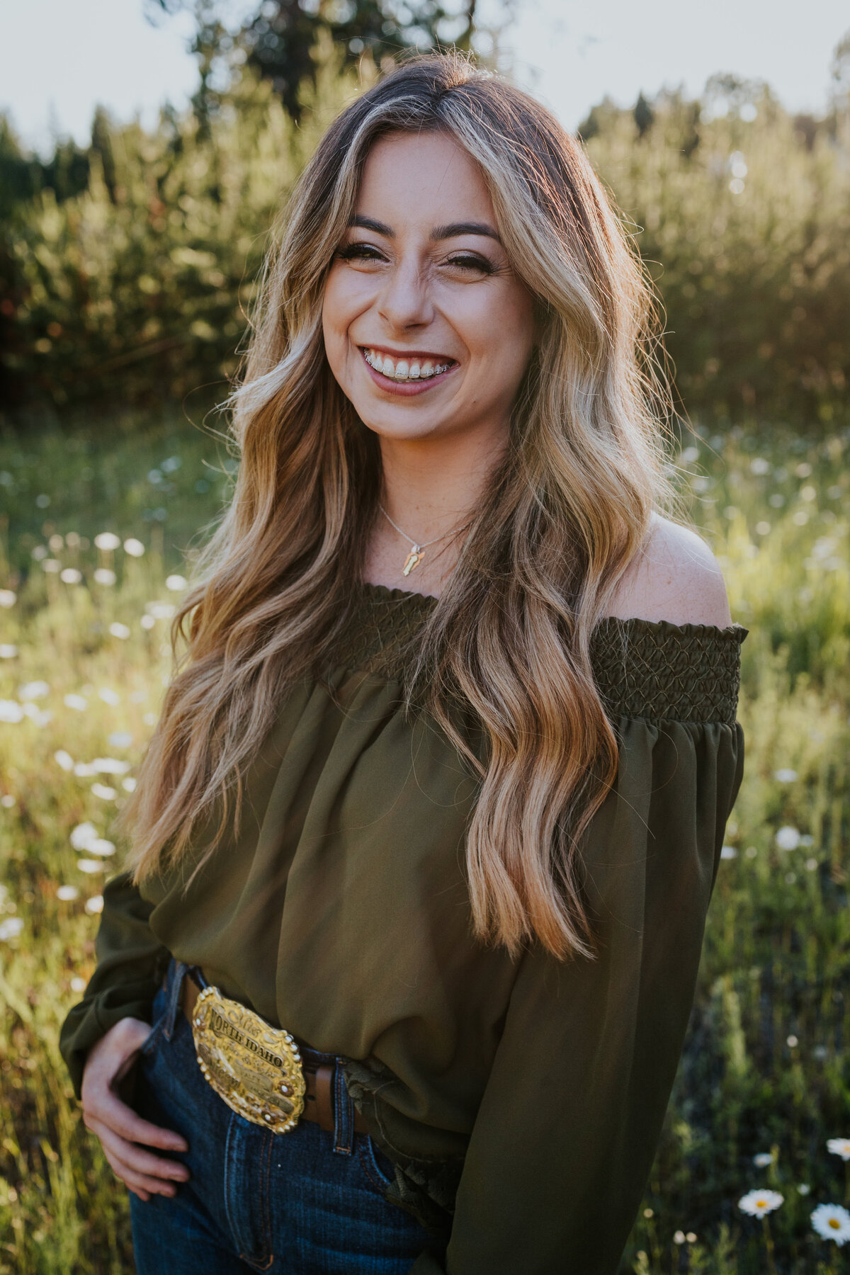 Rodeo queen hooks thumb in jeans while she smiles at camera.