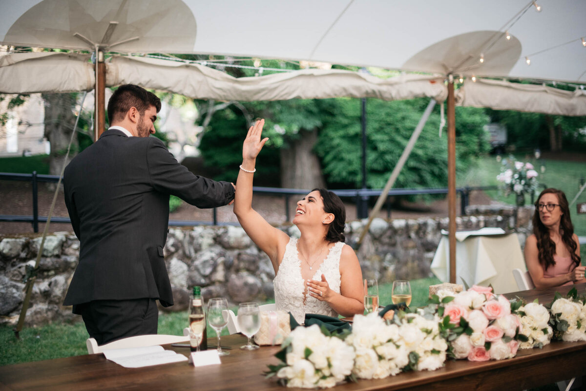 bride and groom high five in tented wedding reception in boston